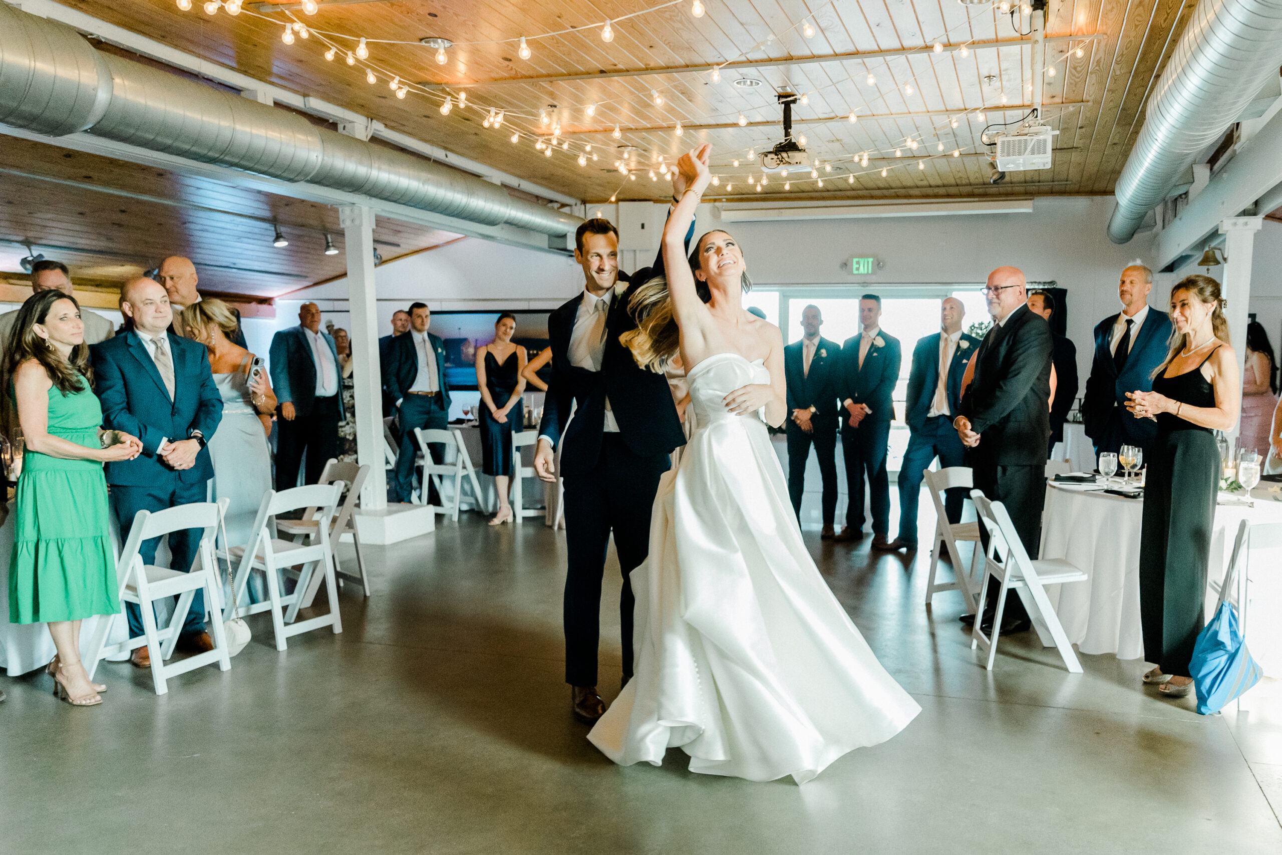 A couple spins happily on the dance floor as their guests cheer for them at an Annapolis waterfront wedding.